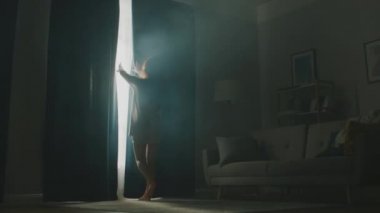 Güzel Genç Esmer Perdeleri açıyor, Sabah Güneşinin içeri girmesine izin veriyor, Sıcak Oturma Odası 'nda mutlu bir şekilde dans ediyor. Şehvetli Kız Erken Kalkıyor ve Yeni Günü Kutluyor. Yavaş Hareket Düşük Açı Kamera Görüntüsü