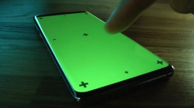 Yakın çekim Macro: Modern Yeşil Model Akıllı Ekran Telefonu Masada Uzanıyor, İnsan Kullanıyor. Hareketler yapan kişi: tokatlamak, dokunmak, itmek, kaydırmak. Kolay Kullanım için Hareket İzleme Noktaları ile Krom Anahtar