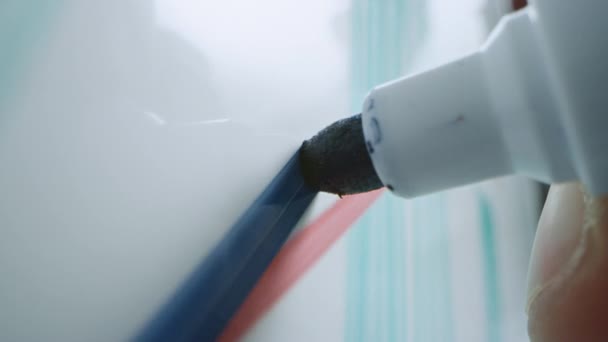 Makroaufnahme eines blauen Marker-Stifts, der mit einer Hand gehalten wird. Person zeichnet Graphen auf einem Whiteboard und fügt ein Häkchen ein. Bleistift wird mit der Kamera verbunden. Gepackter Schuss. — Stockvideo