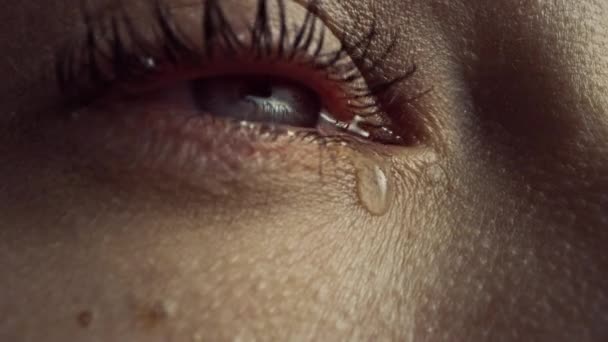 Primer plano Macro Zoom Shot of a Crying Eye. Joven hembra hermosa con pigmentación de color azul claro natural, amarillo y marrón en el iris. La máscara se aplica a las pestañas. Las lágrimas fluyen hacia abajo . — Vídeo de stock