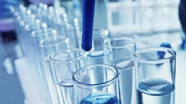 Фармацевтическая лаборатория: Pipette Dropping Blue Liquid into Test Tubes, Medical Research, Analysis. Scientific Lab; Dropper Fills Sample Tubes with Innovative DNA Study Solution. Макро крупным планом — стоковое видео
