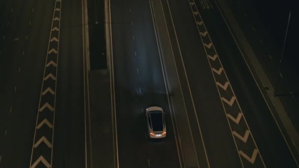 Aerial Drone Widok na nowoczesny luksusowy biały elektryczny SUV jazdy na autostradzie miejskiej. Akumulator napędzany samochód poruszający się po pustej drodze miejskiej z reflektorami w nocy. Futurystyczny Autonomiczny Samojezdny Samochód. — Wideo stockowe