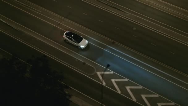 Aerial Drone Widok na nowoczesny luksusowy biały elektryczny SUV jazdy na autostradzie miejskiej. Zasilany baterią samochód z reflektorami Zjazd autostrady w nocy. Futurystyczny Autonomiczny Samojezdny Samochód. — Wideo stockowe