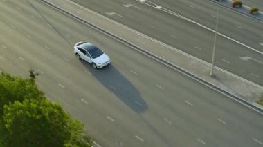 Güneşli bir günde Kentsel Yol 'da Modern Lüks Beyaz Elektrik Geçidi Hava Aracı Görünümü. Pille çalışan araba sinyal aktifleştiriyor ve şeridi değiştiriyor. Panoramik Çatılı Geleceğin SUV 'si.