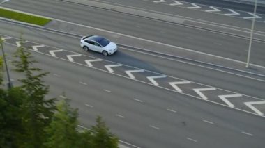 Güneşli bir günde, Şehir Kavşağı 'nda Modern Lüks Beyaz Elektrikli Geçit Sürüşünün Hava Aracı Görünümü. Otoyoldaki bir köprüde pilli araba kullanılıyor. Panoramik Çatılı Geleceğin SUV 'si.