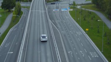 Güneşli bir günde Kentsel Yol 'da Modern Lüks Beyaz Elektrikli Geçit Sürüşü' nün Hava Aracı Takip Çekimi. Pil motorlu araba otobandaki köprüden geçiyor. Otomatik pilotlu gelecekçi SUV.