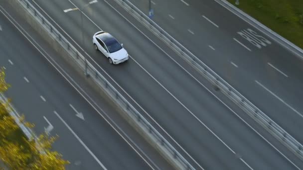 Εναέρια Drone Άποψη ενός σύγχρονου Luxury White Electric Crossover Driving on Urban Road κατά τη διάρκεια μιας συννεφιασμένης ημέρας. Battery Powered Car Εξέρχεται από μια γέφυρα σε μια εθνική οδό. Φουτουριστικό SUV με πανοραμική οροφή. — Αρχείο Βίντεο