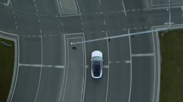 Εναέρια Drone Άποψη ενός σύγχρονου Luxury White Electric Crossover Driving on Urban Road κατά τη διάρκεια μιας ηλιόλουστης ημέρας. Μπαταρία Powered Car περνά Διασταύρωση με φανάρια. Φουτουριστικό SUV με πανοραμική οροφή. — Αρχείο Βίντεο