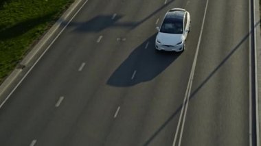 Slow Motion Aerial Drone Modern Lüks Beyaz Elektrikli arazi aracı görüntüsü. Batarya motorlu araç boş yerel yoldan geçiyor. Panoramik Çatı ile Geleceğin Çaprazlaması.