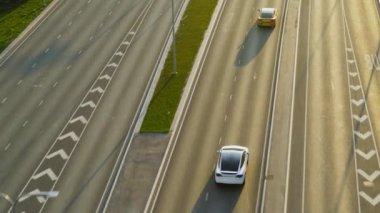 Gündüz vakti Kentsel Yol 'da Günümüz Beyaz Elektrikli SUV' sinin hava aracı görüntüsü. Pille çalışan araba şeridi değiştiriyor ve altın renkli lüks bir Sedan 'ı geçiyor. Panoramik Çatı ile Geleceğin Çaprazlaması.