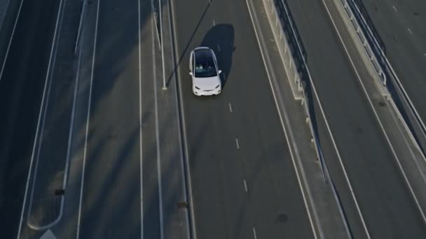 Slow Motion Aerial Drone Vista de un SUV eléctrico blanco de lujo moderno conduciendo por la autopista. Vehículo alimentado por batería que se mueve a través de Empty Express Road. Crossover futurista con techo panorámico . — Vídeos de Stock