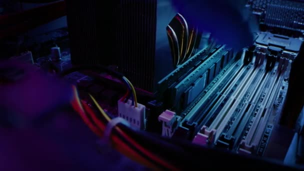 Primo piano Spostamento del colpo macro: le mani della persona installa la memoria RAM nello slot della scheda madre del computer. Tecnico aggiorna il sistema PC / Server. PC di fascia alta moderno girato in neon elegante, colori rosa-blu . — Video Stock