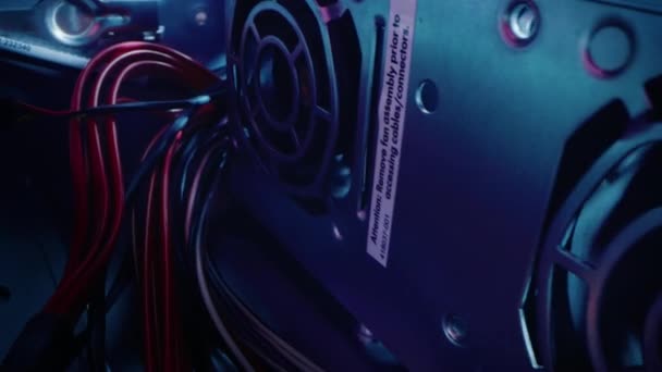 Gros plan Macro Shot : Inside of the Computer Case. Caméra se déplace à côté de la rangée de ventilateurs de refroidissement, avec plusieurs câbles d'alimentation connectés. Appareil électronique intérieur. Élégant néon, noir, rose, bleu 