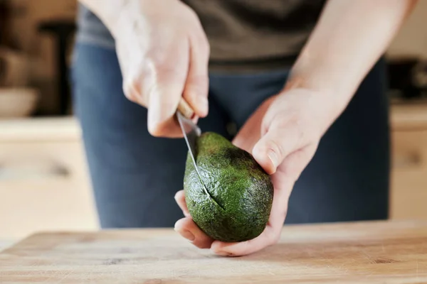 Close up cut avocado knife into hand at home step 2 — Stock Photo, Image
