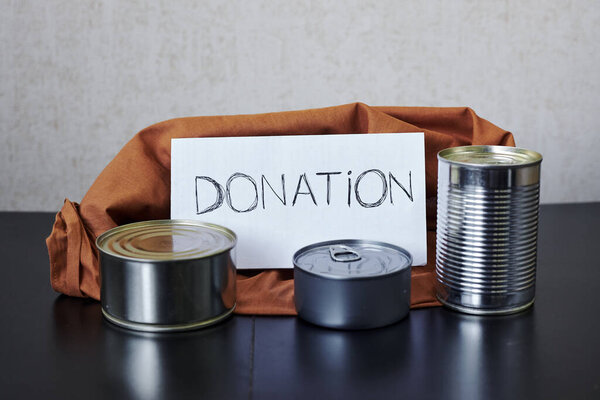 пакет пожертвований оранжевого цвета с консервами и мешком для пожертвований
