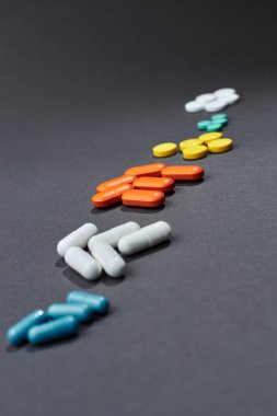 Birkaç avuç dolusu renkli tablet gri bir arkaplana karşı bir satırda yatıyor