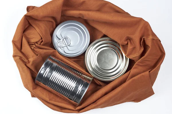 Cans of different sizes and shapes lie in a schopre or a bag on a white background. top view. — Stock Photo, Image