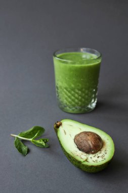 Nane, yarım avokado ve gri arka planda yeşil smoothie ile cam. kopyalama alanı.