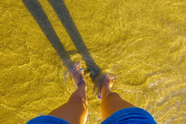 Patas femeninas en playa de arena amarilla — Foto de Stock