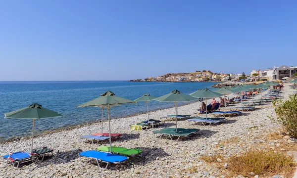 Şemsiye ve güneşlenme turist Paleochora taş beach kasaba adada Crete, Yunanistan
