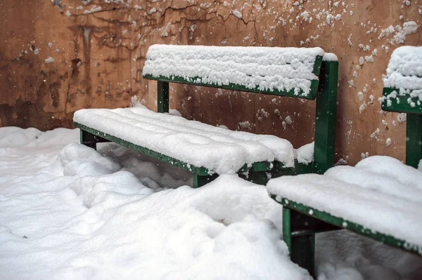 Snow-covered benches near the wall