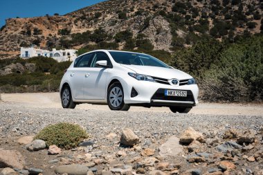 Beyaz Toyota Auris Crete adasının yolda bulutlar arasında park edilmiş kalır. 