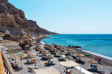 Şezlong ve sunny beach Santorini Adası'nda turistler. 