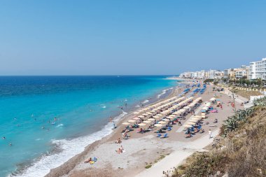 Rodos Adası üzerinde sahip insanlar şeffaf mavi su ile sevinç ar kum plaj.