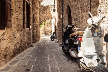 Motosiklet scooter, Rodos'un şehir Rodos, Yunanistan üzerinde dar sokak duvarının yakınında park edilmiş