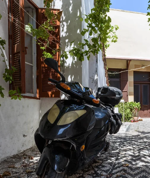 Motorbike parked near wall with beautiful window in Rhodes town on Rhodes island, Greece