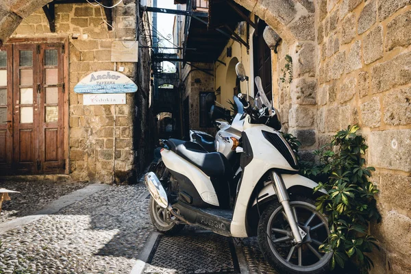 Motorbike scooters are parked near the wall at narrow street of Rhodes town on Rhodes island, Greece