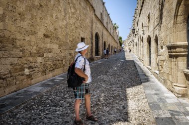 Sırt üstünde onun sırt çantası ile turizm, Rodos'un şehir dar cadde boyunca yürüyor. Rodos, Yunanistan  