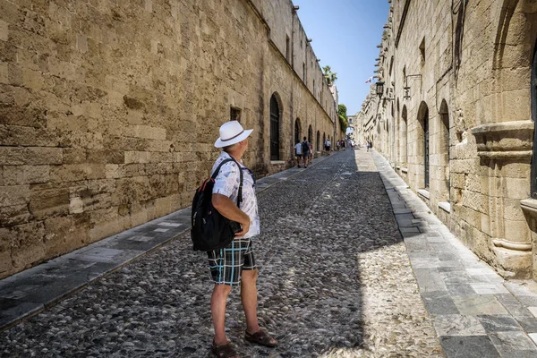 Sırt üstünde onun sırt çantası ile turizm, Rodos'un şehir dar cadde boyunca yürüyor. Rodos, Yunanistan  