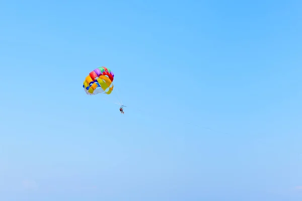 Paracadutista volante con paracadute a colori, isolato su un cielo blu vicino all'isola di Rodi, Grecia — Foto Stock