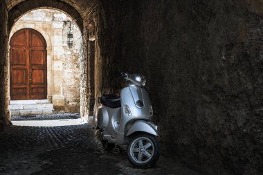 Rhodes, Yunanistan - Ağustos 2017: Motosiklet, Rodos'un şehir bir arka plan eski ahşap kapı ile karanlık Arch. Rodos, Yunanistan