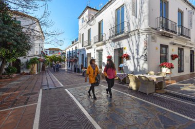 Marbella, İspanya - Aralık 2017: İki kadın evleriyle ile güzel sokak boyunca yürüyüş.