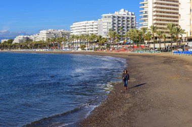 Marbella, İspanya - Aralık 2017: Güzel oteller ve bir ön plan üzerinde yürüyen kadın şehir sahil şeridine.