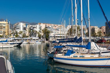 Marbela, İspanya - Aralık 2019: Park etmiş tekneleri ve arka planda evleri olan liman.