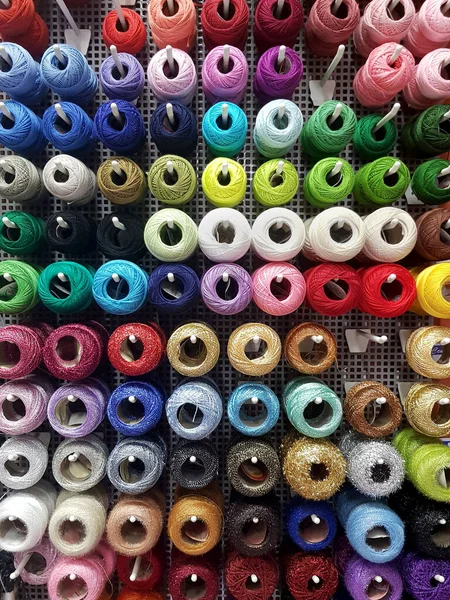 Wall of cotton reels, lots of colorful spools of thread displayed at the notions store, many sewing accessories for art and crafts, background, haberdashery texture