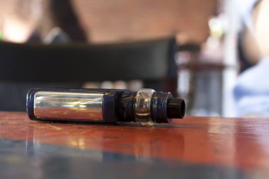 Yeni modern, parlak elektronik e-sigara kutusu ham kulüp / bar çevresi makrosunun üzerinde duruyor, yakın plan. Sigara ya da tütün rehabilitasyonu, aksesuar buharı ve teknoloji soyut kavramı, hiç kimse