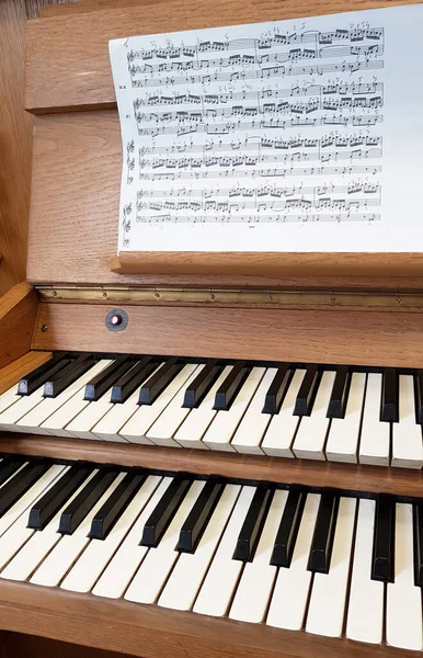 Pipe organ with sheet music, finger comments written. Two keyboards of traditional church pipe organ. Learning to play, practicing on an unusual instrument concept