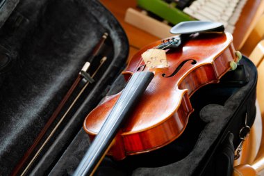 Keman, keman, fiyonk açık siyah bir çantada masanın üstünde, arkada küçük bir ksilofon. Klasik müzik enstrümanları grubu konsepti, hiç kimse. Seyahat için güvenli araç deposu