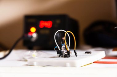 Basit elektrik devresi, elektrik bileşenleri, kablolar, diyot, rezistanslar, arka planda lehimleme istasyonu, proje, elektrikçi öğrenci çalışma alanı konsepti, makro, kapatma