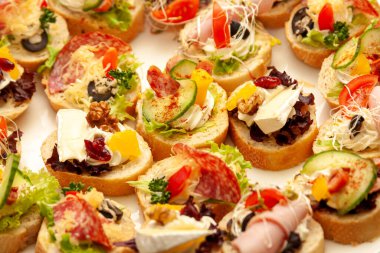 Bir sürü küçük, tatlı sandviçler, gurme açık büfe yakın çekim, yemek fotografı makrosu. Peynirli, sebzeli, ekmekli sağlıklı, lezzetli ikramlar. Şölen mutfağı, hızlı atıştırma konsepti.