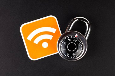 Kablosuz ağ güvenliği basit soyut bir kavram. Kablosuz bağlantı sinyali sembolü ve siyah arka planda duran şifreli bir asma kilit. Halka açık bölgelerde güvenli, mobil internet veri güvenliği, hackleme
