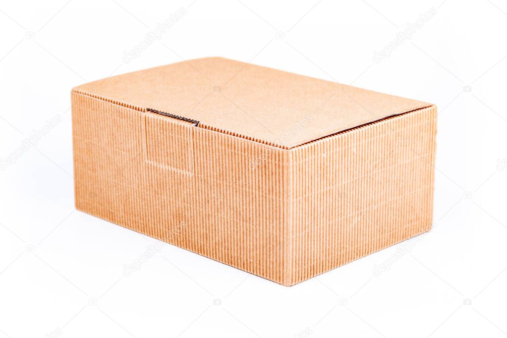 Simple single small brown corrugated cardboard delivery carton box with a lid closed isolated on white background, object cut out, closeup. Shipping, transportation and packaging, storage concept