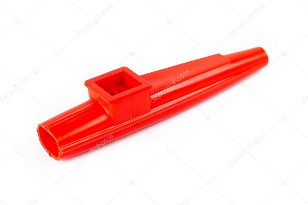 Red kazoo, plastic traditional musical instrument object isolated on white, cut out, closeup. Kids wind instruments with vibrating membrane, unique membranophones, noisemakers simple concept, nobody