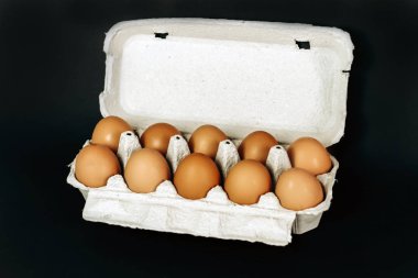 Siyah arka planda gri bir sandıktaki tavuk yumurtaları.