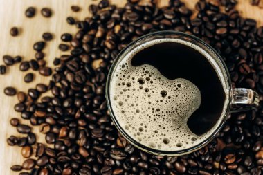 Ahşap arka planda bir sürü kahve çekirdeği var. Bir fincan taze kahve.