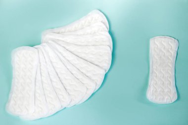 Kadınsı hijyen malzemelerinin düzlüğü. Turkuaz arka plandaki kritik kadın günlerinin ayrıntıları. Kadınlar için contalar, sağlık